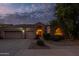 Inviting home featuring a well-maintained front yard, three-car garage, and warm exterior lighting at 9678 E Voltaire Dr, Scottsdale, AZ 85260