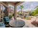 Covered patio with comfortable seating and an outdoor table, overlooking the pool and backyard landscaping at 9678 E Voltaire Dr, Scottsdale, AZ 85260