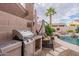 Outdoor kitchen and patio area featuring a grill, swing, and view of the backyard pool with mature landscaping at 9678 E Voltaire Dr, Scottsdale, AZ 85260