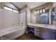 The bathroom features a soaking tub, tile flooring, and an extended vanity with a sink at 125 N 22 Pl # 14, Mesa, AZ 85213