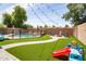 Spacious backyard with artificial turf, pool, fire pit, and charming string lights at 13709 W Rovey Ave, Litchfield Park, AZ 85340