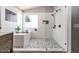 Bright bathroom with an open shower, soaking tub, stylish tile, and contrasting fixtures at 13709 W Rovey Ave, Litchfield Park, AZ 85340