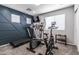 Carpeted exercise room with multiple windows, blue accent wall and a variety of workout equipment at 13709 W Rovey Ave, Litchfield Park, AZ 85340