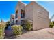 Residential two-story building featuring tan stucco and blooming bushes underneath a bright blue sky at 14910 N Kings Way # 105, Fountain Hills, AZ 85268