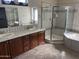 Well-appointed bathroom featuring double vanities, tiled counters, a glass-enclosed shower, and a soaking tub at 15314 W Camino Estrella Dr, Surprise, AZ 85374