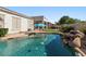 Backyard pool with beautiful rock waterfall feature, surrounded by lush greenery and patio furniture at 1680 S Arroyo Ln, Gilbert, AZ 85295