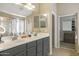 Bathroom featuring a double sink vanity, large mirror, and walk-in closet at 17820 W Charter Oak Rd, Surprise, AZ 85388