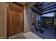 Inviting front porch features a wooden door, seating area, and a view of the illuminated exterior at 18121 W Las Cruces Dr, Goodyear, AZ 85338