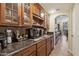 Coffee bar in the kitchen with attractive wood cabinets, granite countertops, and decorative glassware at 18121 W Las Cruces Dr, Goodyear, AZ 85338