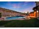 Backyard pool area with artificial turf, lounge chairs, outdoor fireplace, and scenic desert views for ultimate relaxation at 18121 W Las Cruces Dr, Goodyear, AZ 85338