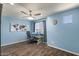 Comfortable bedroom featuring hardwood floors, a ceiling fan, a desk, and blue accent walls at 23081 S 223Rd Way, Queen Creek, AZ 85142
