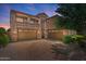 Home exterior featuring a three-car garage, balconies, desert landscaping, and a brick driveway at 23081 S 223Rd Way, Queen Creek, AZ 85142