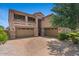 Home exterior featuring a three-car garage, balconies, desert landscaping, and a brick driveway at 23081 S 223Rd Way, Queen Creek, AZ 85142