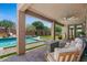 Inviting covered patio featuring brick pavers, comfortable seating, and a view of the sparkling pool and lush backyard at 23081 S 223Rd Way, Queen Creek, AZ 85142