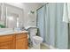 Bright bathroom features wood cabinetry, tiled floors, shelving, and shower with gray curtain at 23645 W Parkway Dr, Buckeye, AZ 85326