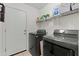 Functional laundry room with side-by-side washer and dryer, storage shelves, and neutral paint at 23645 W Parkway Dr, Buckeye, AZ 85326