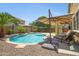 Inviting backyard pool area with a waterfall feature, lounge chairs, and a large sun umbrella at 23733 S 209Th Pl, Queen Creek, AZ 85142