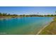 Scenic community pond with clear turquoise water, lush green landscaping and an American flag at 24746 N 171St Ln, Surprise, AZ 85387