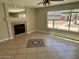 Cozy living room with a fireplace, tile flooring, and large windows offering views of the backyard at 2634 S 63Rd Dr, Phoenix, AZ 85043