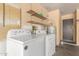 Functional laundry area equipped with Amana washer and dryer and shelving units for additional storage at 3825 W Royal Palm Rd, Phoenix, AZ 85051