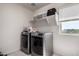 Efficient laundry room with modern washer and dryer, shelving, and natural light at 40213 W James Ln, Maricopa, AZ 85138