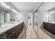 Bright bathroom featuring double sinks, sleek cabinetry, tile floors, and a mirrored wall at 4353 W Villa Rita Dr, Glendale, AZ 85308