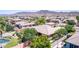 An aerial view of a home in a suburban neighborhood, featuring a pool, green landscaping, and mountain views at 4404 W Olney Ave, Laveen, AZ 85339