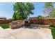 Outdoor backyard featuring a grill, fireplace, seating, and lush landscaping at 4404 W Olney Ave, Laveen, AZ 85339