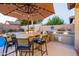 Outdoor kitchen area with a large grill, bar seating, and an umbrella overlooking the backyard pool at 4422 E Spur Dr, Cave Creek, AZ 85331