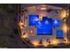 Aerial view of the pool area featuring a hot tub, fire pit, and lounge seating all illuminated for a relaxing evening atmosphere at 4605 E Swilling Rd, Phoenix, AZ 85050