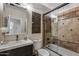 Cozy bathroom featuring a modern vanity and a shower-tub combo with decorative stone tiling at 4605 E Swilling Rd, Phoenix, AZ 85050