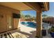 A luxurious pool area featuring travertine tile, a TV and a mosaic-tiled pool surface, all in a serene outdoor setting at 4605 E Swilling Rd, Phoenix, AZ 85050