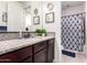 Stylish bathroom with granite counters, wooden vanity, modern lighting, and patterned shower curtain at 5212 S Seton Ct, Gilbert, AZ 85298
