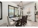 Bright dining room featuring dark wood table, chairs, modern light fixtures, and large windows at 5212 S Seton Ct, Gilbert, AZ 85298