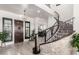 Elegant foyer with a curved staircase, stone accent wall, and a stylish chandelier creating a grand entrance at 5212 S Seton Ct, Gilbert, AZ 85298