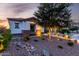 Inviting single story home with drought tolerant landscaping, stone accents and ambient outdoor lighting at dusk at 5212 S Seton Ct, Gilbert, AZ 85298