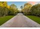 Long brick driveway leads to a secluded home surrounded by lush greenery and mature trees at 5929 E Indian School Rd, Phoenix, AZ 85018