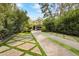 Long driveway featuring decorative pavers and grass, leading to a beautifully landscaped home at 5929 E Indian School Rd, Phoenix, AZ 85018