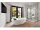 Bright bathroom featuring a soaking tub, glass shower, and an outdoor view at 5929 E Indian School Rd, Phoenix, AZ 85018