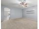 Inviting living room with ceiling fan, shelves, carpeted floor, and an open doorway to kitchen at 7319 S 56Th Dr, Laveen, AZ 85339