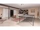 Finished basement living room with exposed beams, bookshelves, and ping pong table at 8302 S Jentilly Ln, Tempe, AZ 85284