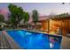 Backyard swimming pool featuring a covered bar area for outdoor entertaining at dusk at 8302 S Jentilly Ln, Tempe, AZ 85284