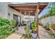 Covered backyard patio with lush garden, potted plants, wooden pergola, and comfortable outdoor seating at 919 E Villa Maria Dr, Phoenix, AZ 85022