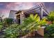 Backyard with a covered patio, landscaped garden, and mature palm trees with a colorful sunset backdrop at 13448 W Miner Trl, Peoria, AZ 85383