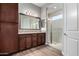 Modern bathroom features double sink vanity with dark cabinetry, large mirror, and walk-in shower at 13448 W Miner Trl, Peoria, AZ 85383