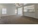 Neutral living room with a ceiling fan, carpet, and open access to kitchen at 15364 W Acapulco Ln, Surprise, AZ 85379
