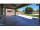 Covered patio area overlooking a spacious backyard with artificial grass and mature trees at 16475 N 183Rd Dr, Surprise, AZ 85388