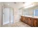 Bright bathroom featuring a double vanity, large mirror, and a glass-enclosed shower at 16475 N 183Rd Dr, Surprise, AZ 85388