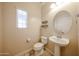 Compact powder room with a pedestal sink, round mirror, floating shelves, and a window for natural light at 16475 N 183Rd Dr, Surprise, AZ 85388