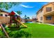 Gathering-friendly backyard featuring a pool, swing set, patio seating, and lush artificial turf, perfect for outdoor fun at 16565 W Garfield St, Goodyear, AZ 85338
